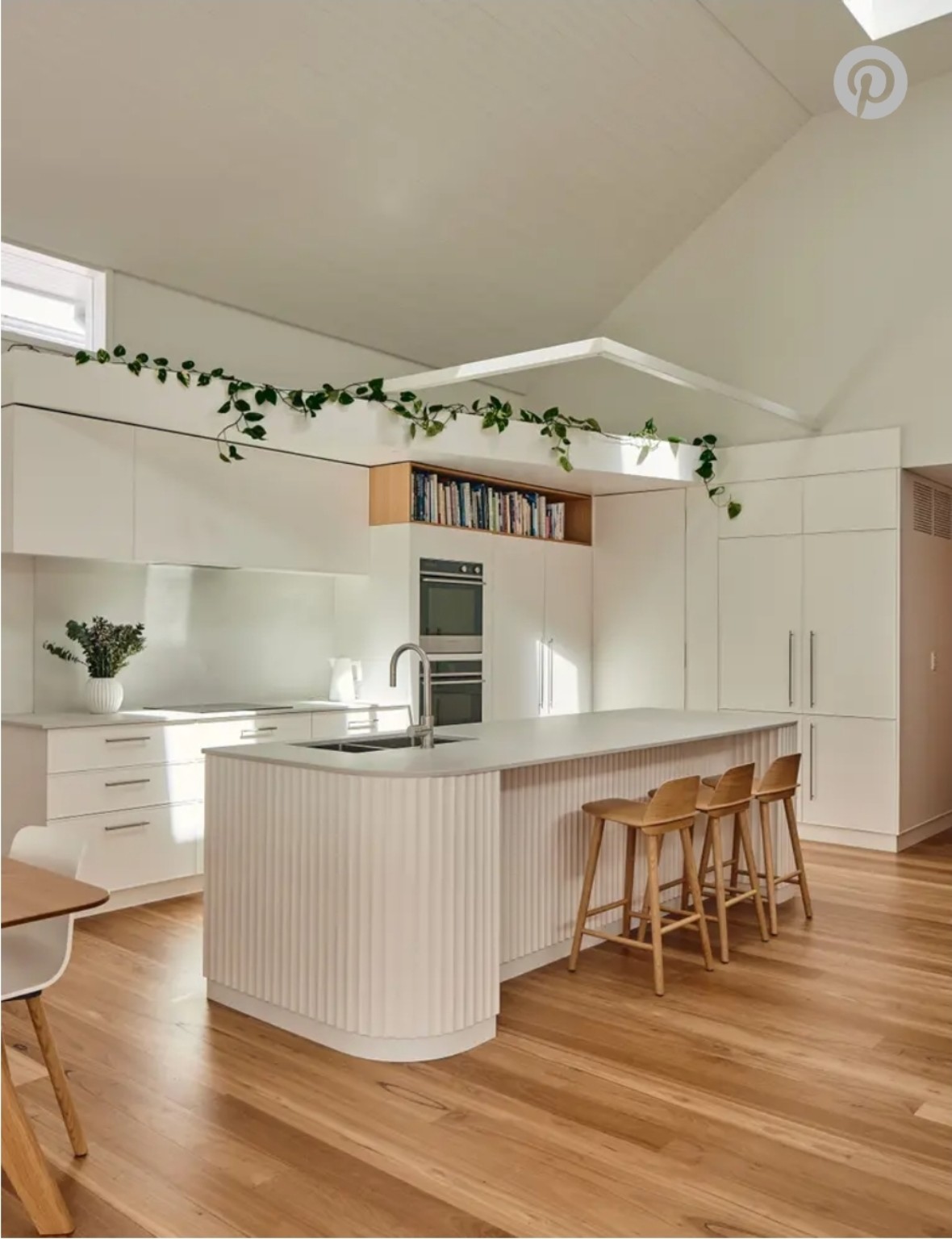 White kitchen with rounded island and timber floor